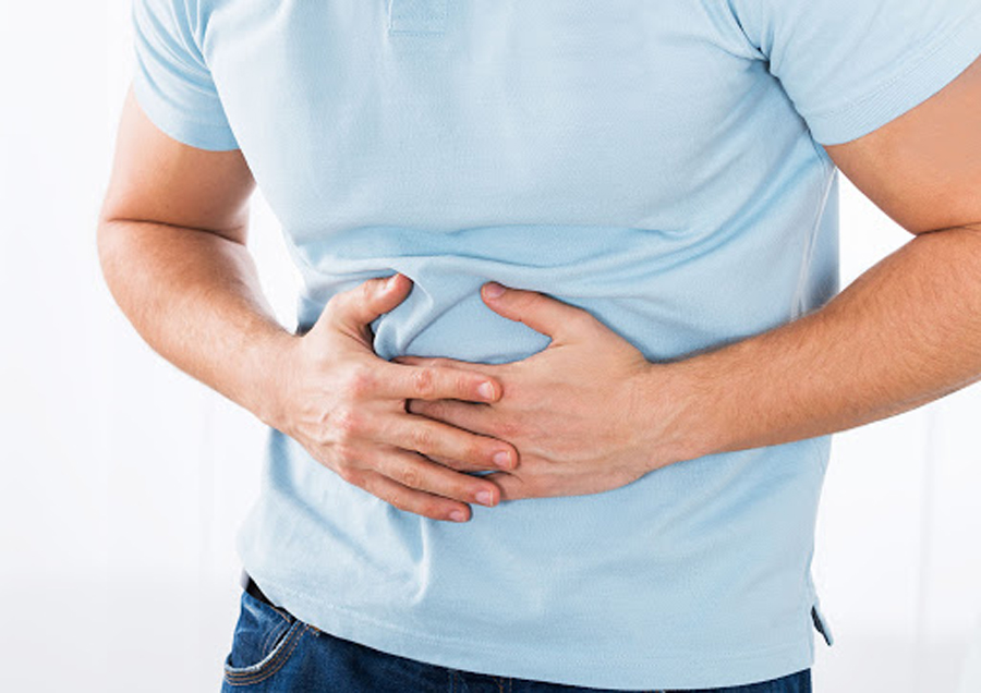 Close-up Of Young Man Suffering From Stomach Ache Standing At Home
